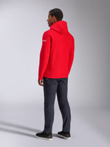 Sudadera con capucha Alpinestars Frontal, sudadera de forro polar roja, vista posterior que muestra el logotipo de la marca en blanco en la manga, usada con pantalones vaqueros oscuros y calzado negro, ropa urbana de estilo casual motorsport