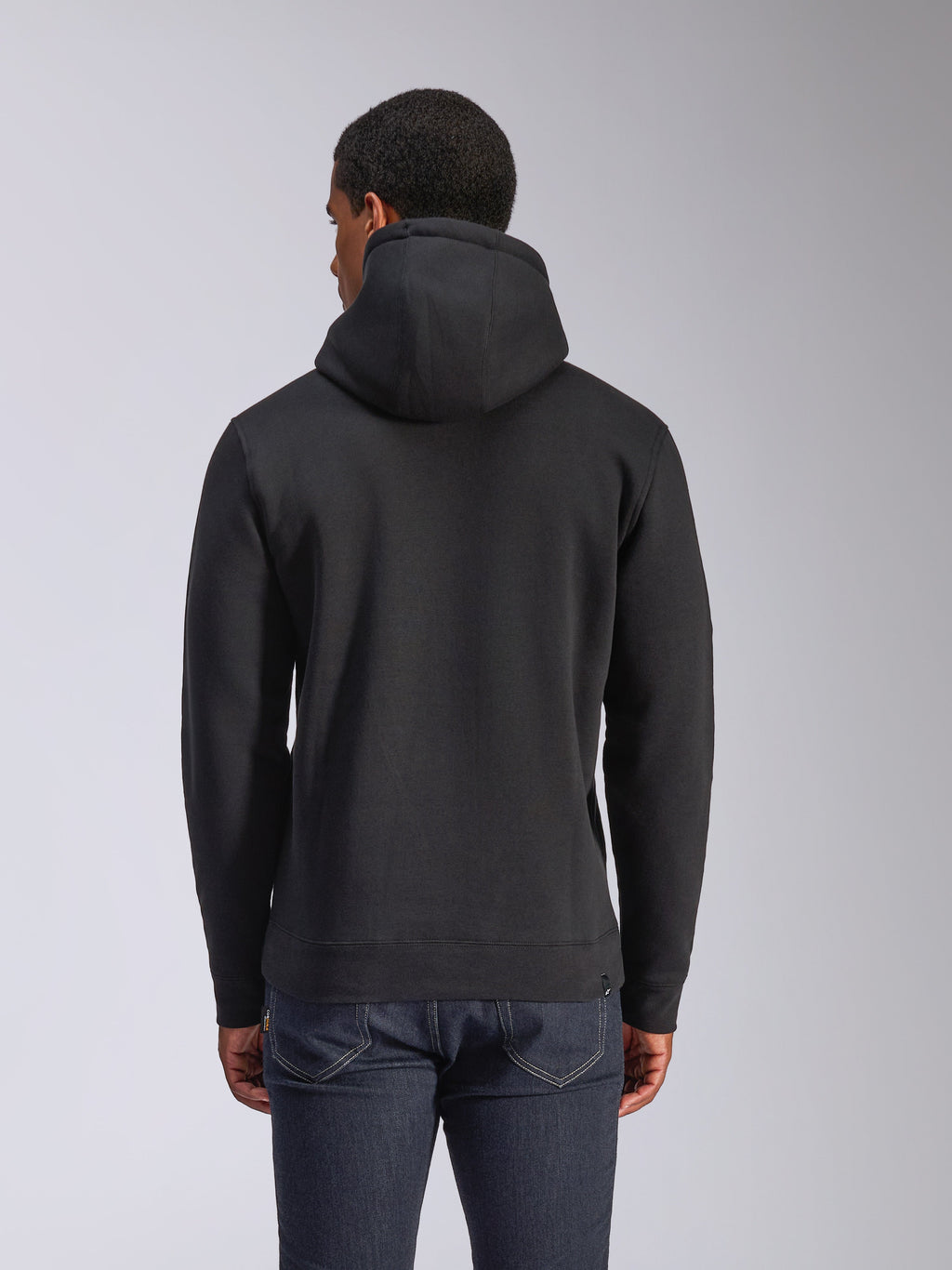 Sudadera con capucha Alpinestars Blaze V3, vista posterior de sudadera negra de felpa, ropa de estilo urbano casual, con puños y dobladillo de canalé, capucha con forro de jersey, usada con vaqueros azul oscuro