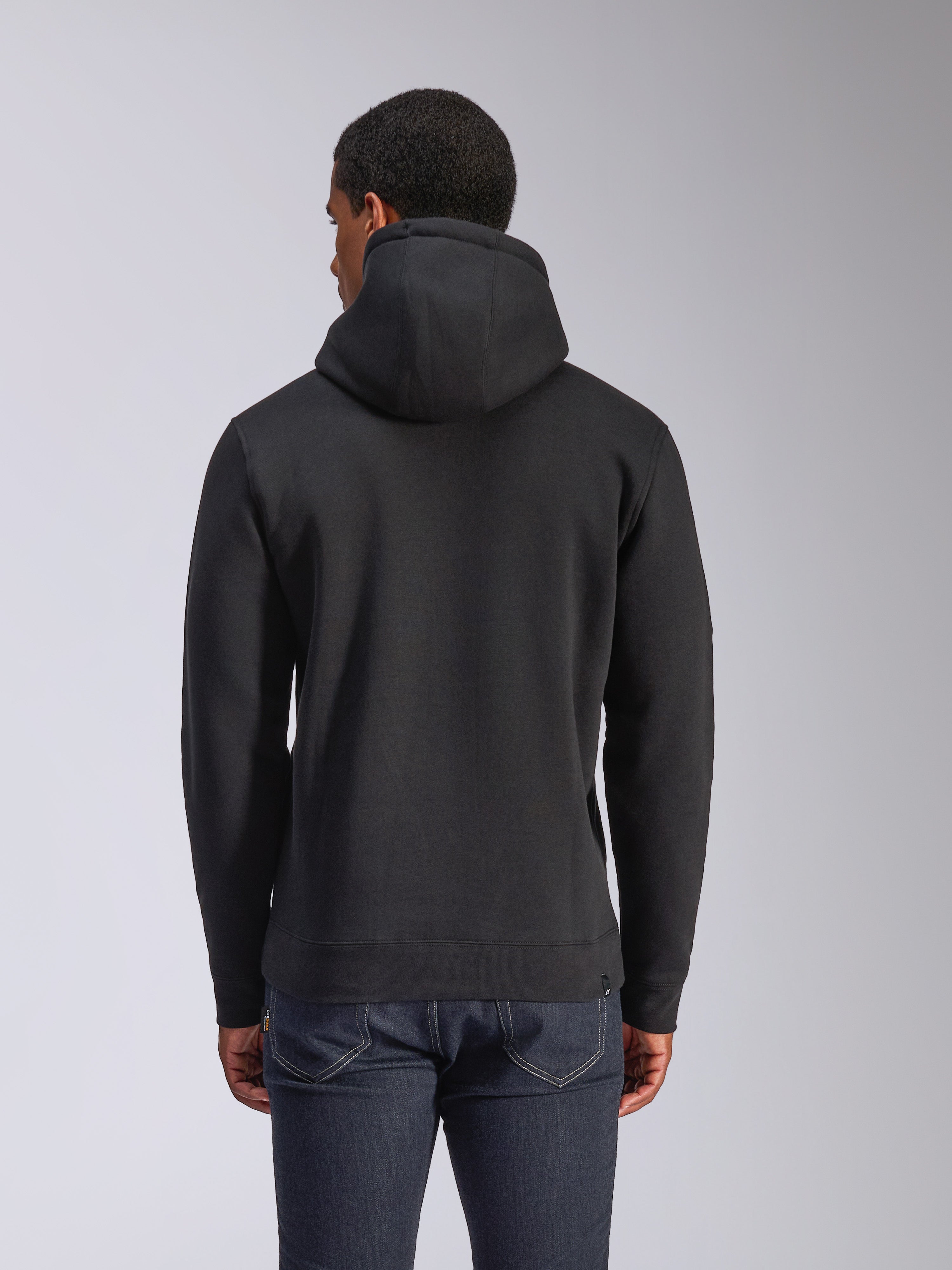 Sudadera con capucha Alpinestars Blaze V3, vista posterior de sudadera negra de felpa, ropa de estilo urbano casual, con puños y dobladillo de canalé, capucha con forro de jersey, usada con vaqueros azul oscuro