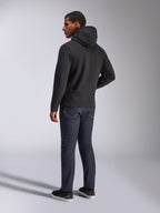 Alpinestars Blaze V3 Hoodie, vista posterior de un hombre con la sudadera negra, combinada con vaqueros oscuros y zapatillas negras, ropa urbana casual de inspiración motorsport