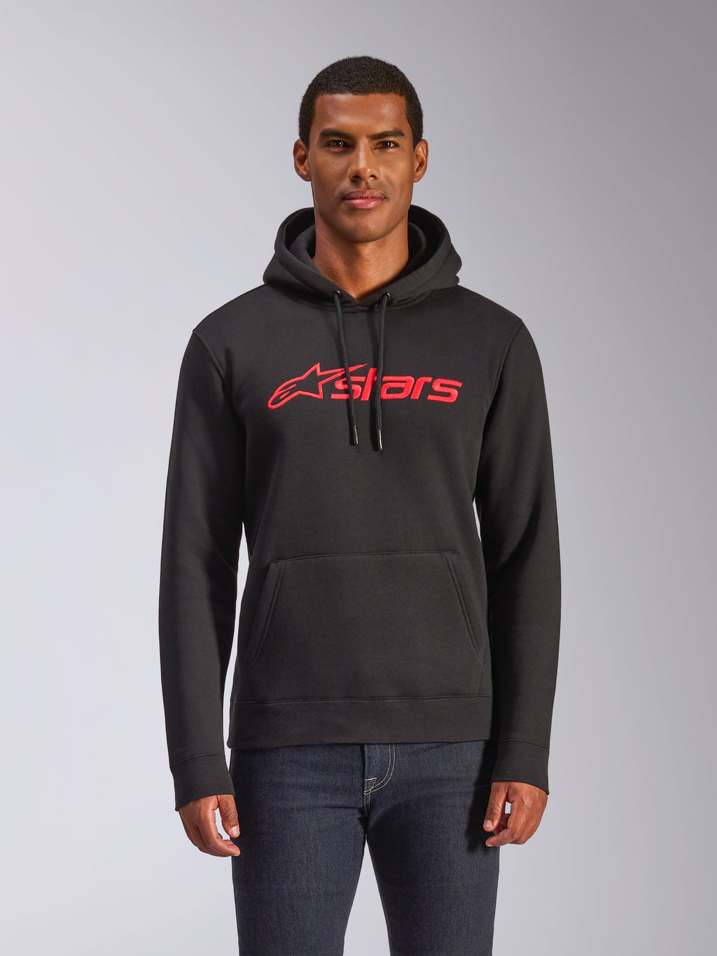 Sudadera con capucha Alpinestars Blaze V3, sudadera de forro polar para hombre, negra con logotipo de estrella Alpinestars en rojo, usada por un hombre con vaqueros oscuros, con capucha con cordón y bolsillo de canguro, ropa urbana casual inspirada en el automovilismo