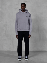 Alpinestars Essentials Ageless Hoodie, Silver, male model wearing casual streetwear, small black Alpinestars logo on chest, front kangaroo pocket, minimalist design, paired with black pants and sneakers.