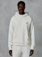 Alpinestars Essentials Ageless Hoodie, color blanco roto, usada por modelo masculino, pequeño logotipo negro en el pecho, bolsillo tipo canguro frontal, manga larga, ropa urbana casual inspirada en el automovilismo