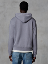 Sudadera con capucha y cremallera Alpinestars Essentials Ageless, plateada, vista trasera, estilo urbano casual, ajuste relajado con acabado de lavado a la piedra, combinada con vaqueros azules y camiseta blanca debajo