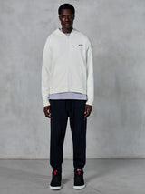 Alpinestars Essentials Ageless Zip Hoodie, Off White full-zip hoodie, relaxed fit with small black logo on chest, worn with black sweatpants and sneakers, casual motorsport-inspired streetwear.