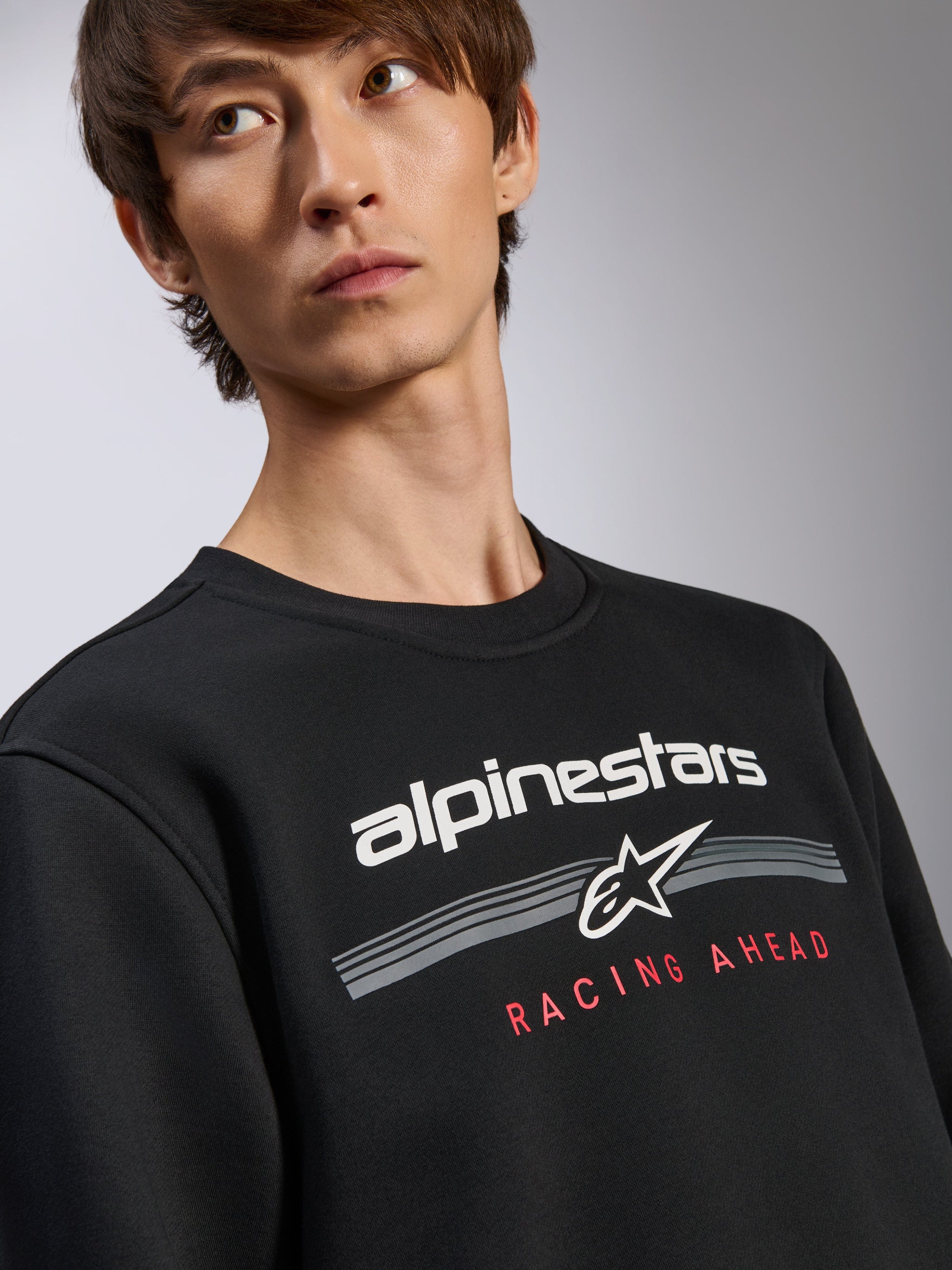 Sudadera Alpinestars Bettern Crew, sudadera negra de cuello redondo, logotipo blanco de Alpinestars con el gráfico de texto rojo 'Racing Ahead', estilo urbano casual inspirado en el motorsport