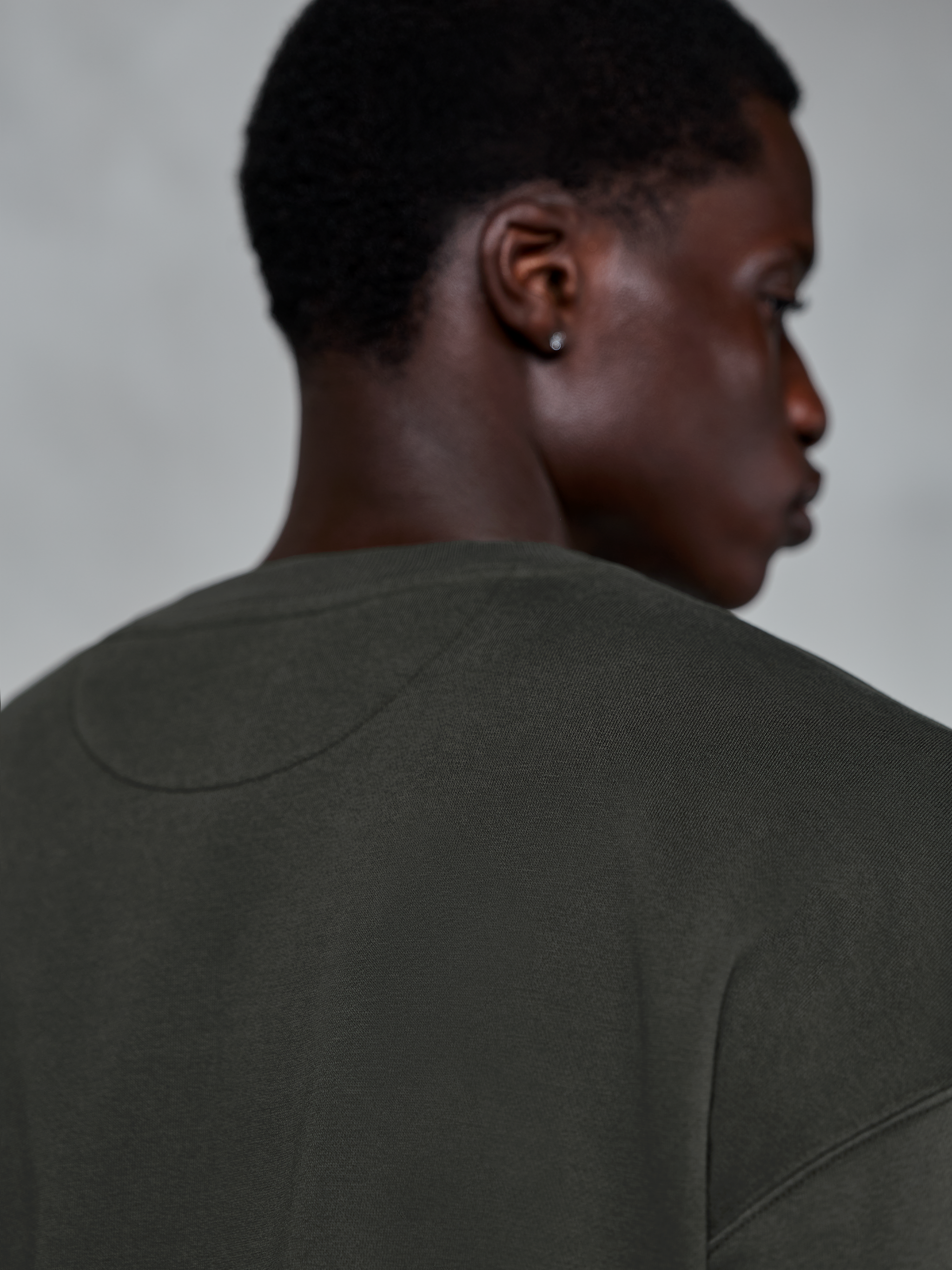 Alpinestars Essentials Ageless Crew, sudadera premium de cuello redondo en color Off Black, primer plano de la parte posterior del cuello y la zona del hombro, textura de forro polar compacto con lavado a la piedra, estilo urbano casual de inspiración motorsport