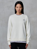 Alpinestars Essentials Ageless Crew, sudadera de cuello redondo, blanco roto, con un pequeño logotipo de Alpinestars en negro en el pecho, ropa casual de estilo de vida modelada por una mujer