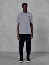 Alpinestars Essentials Ageless SS Tee, camiseta de manga corta, plateada, con un pequeño logotipo negro en el pecho, combinada con pantalones joggers y zapatillas negras, estilo streetwear casual de motorsport