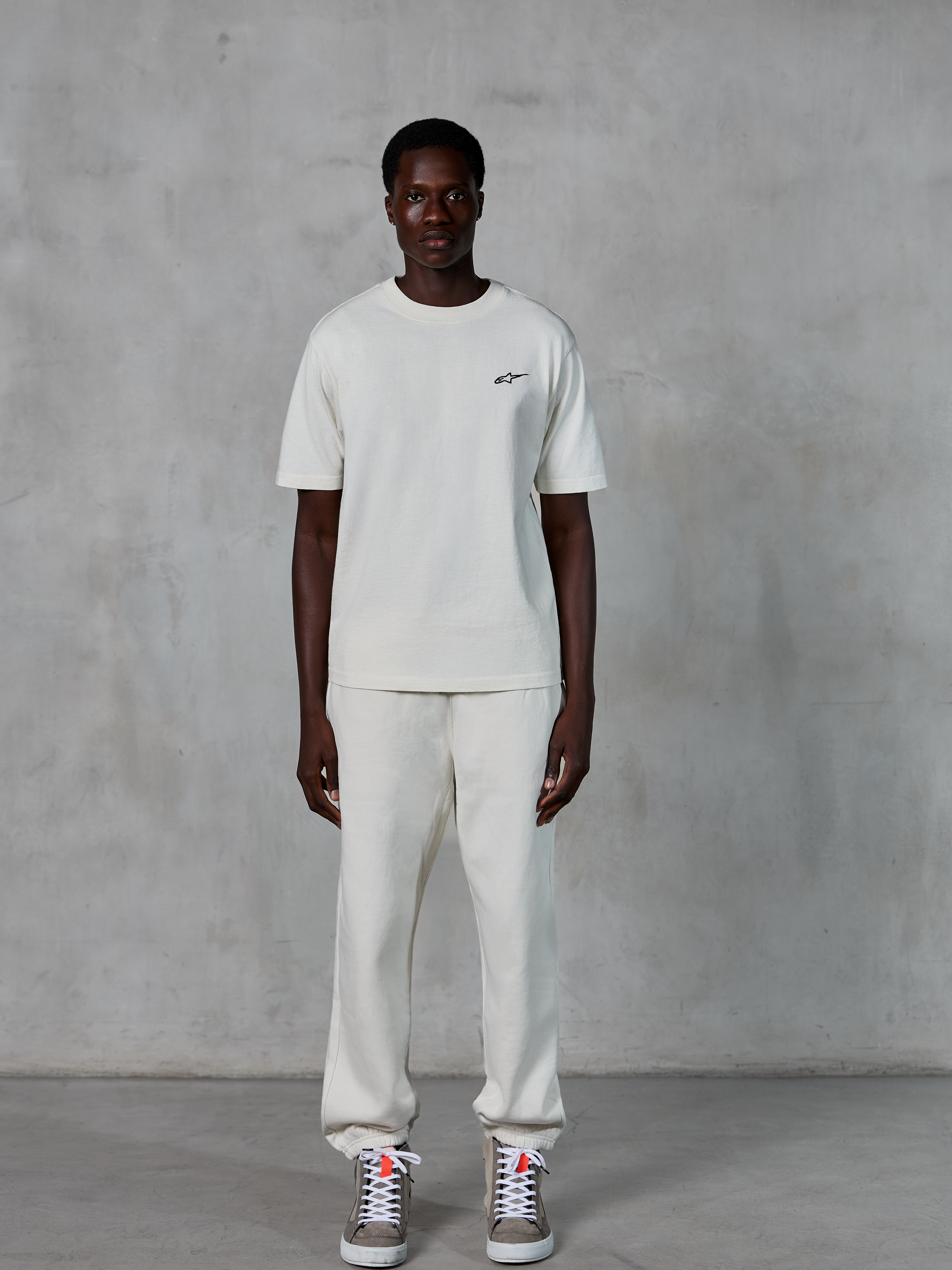 Alpinestars Essentials Ageless SS Tee, camiseta de manga corta, blanco roto, con un pequeño logotipo de Alpinestars en negro en el pecho, combinada con joggers a juego y zapatillas para un look de estilo de vida relajado