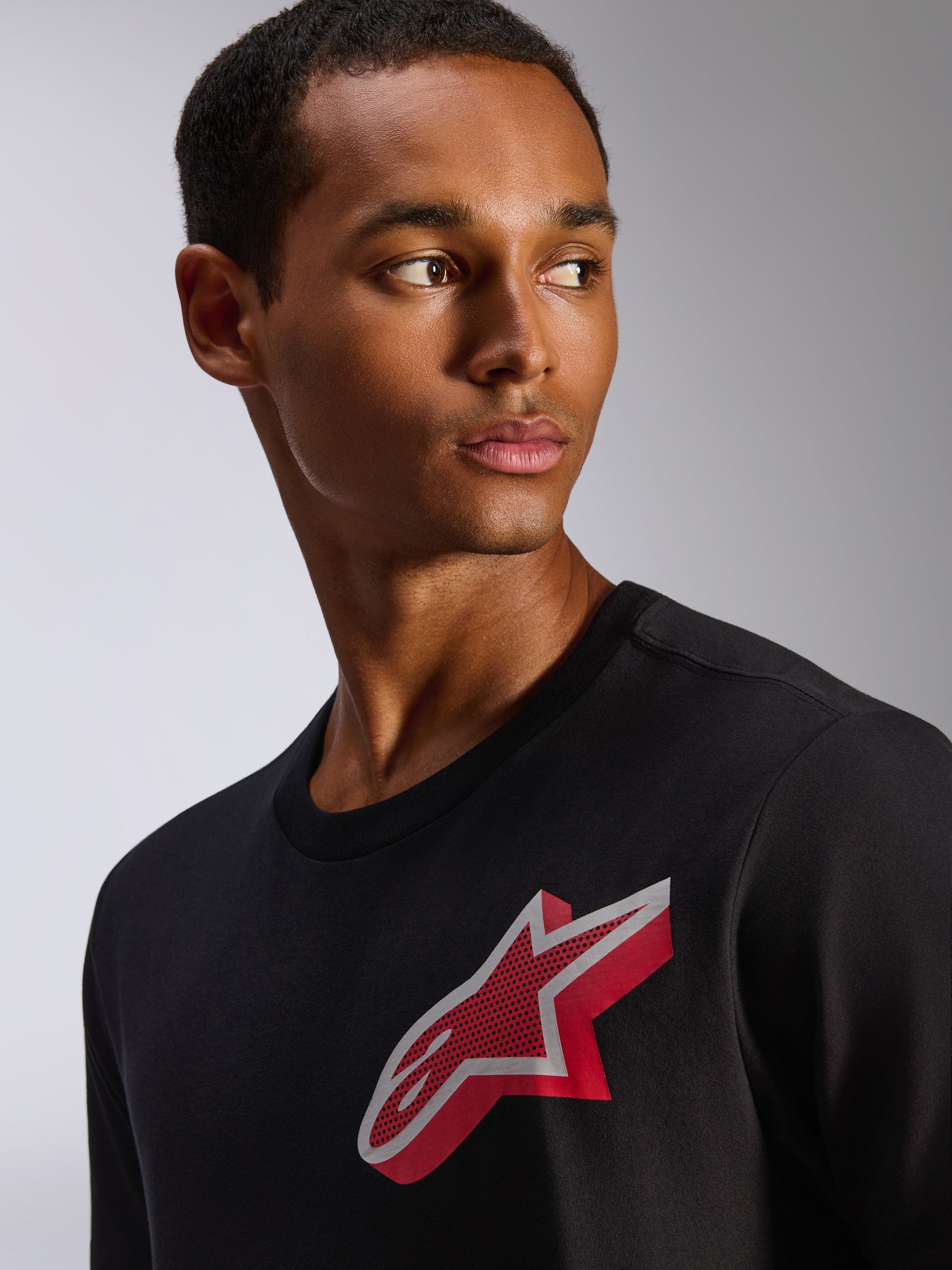 Camiseta Alpinestars Shaded CSF, camiseta de manga corta, negra, con el logotipo Astars en lámina con degradado rojo y blanco en el pecho, ropa casual inspirada en el motorsport vestida por un modelo masculino