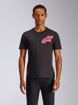 Camiseta Alpinestars Shaded CSF, camiseta de manga corta, negra, logotipo Astars en lámina roja con degradado inclinado, vestida por un modelo con pantalones negros, estilo casual motorsport streetwear