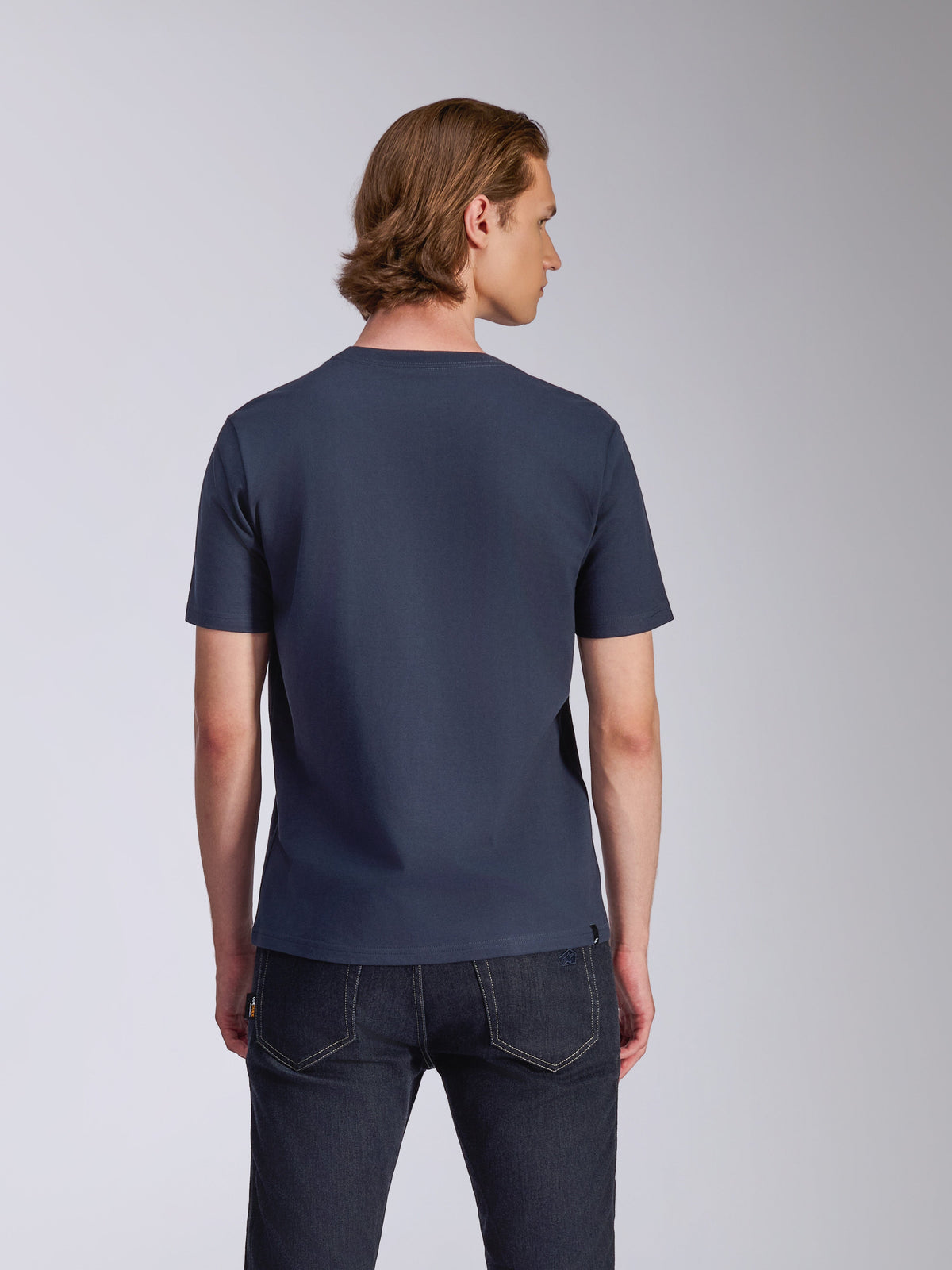 Alpinestars Fasting CSF Tee, camiseta de manga corta, azul marino, vista posterior, usada por un modelo con vaqueros oscuros, ropa urbana casual inspirada en el automovilismo
