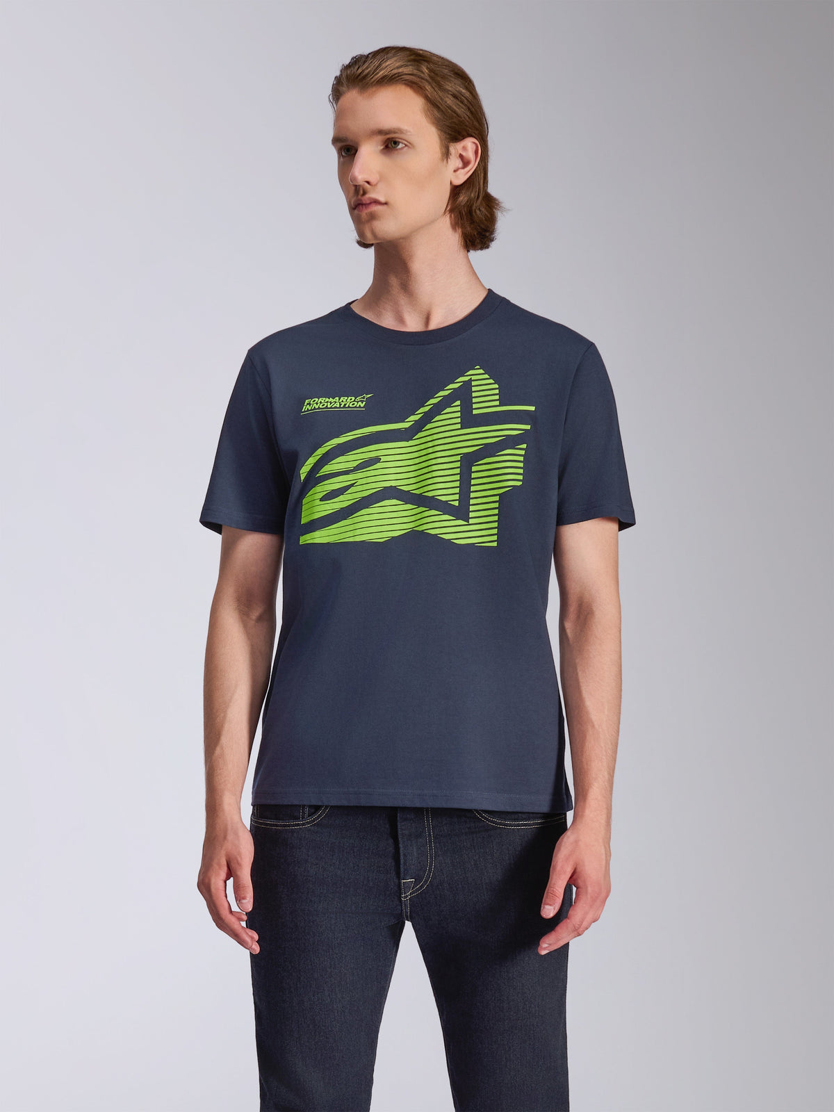 Camiseta Alpinestars Fasting CSF de manga corta, azul marino, con gran logotipo geométrico de Astars en verde lima, usada por un modelo con vaqueros oscuros, estilo streetwear casual de motociclismo