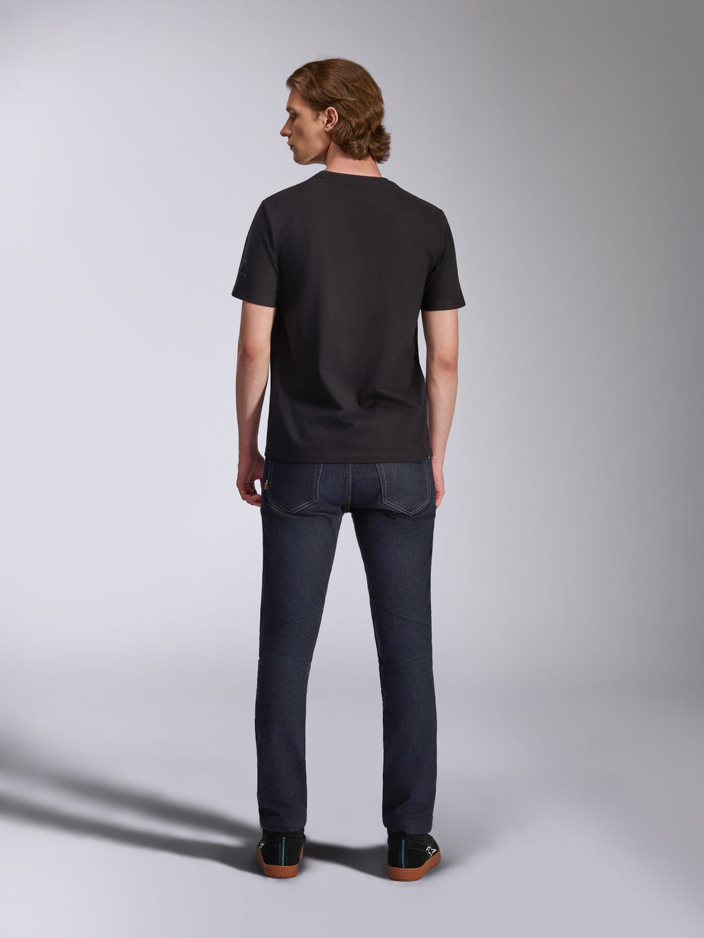 Alpinestars Global CSF Tee, Short Sleeve T-Shirt in Black, back view of male model wearing the shirt with dark denim jeans, casual motorsport-inspired streetwear