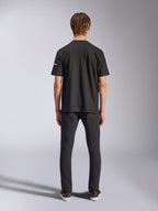 Alpinestars Frontal CSF Tee, camiseta de manga corta, negra, vista posterior en modelo con vaqueros negros, ropa de calle casual de alto rendimiento con detalle de logotipo blanco pequeño en la manga