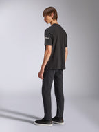 Camiseta Alpinestars Frontal CSF, camiseta de manga corta, negra, logotipo astars blanco en la manga, usada por un modelo con pantalones y zapatos negros, diseño casual inspirado en el automovilismo