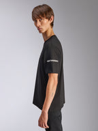 Camiseta Alpinestars Frontal CSF, camiseta de manga corta, negra, logotipo blanco de Alpinestars en la manga, usada por un modelo en vista de perfil, ropa urbana casual de alto rendimiento motorsport