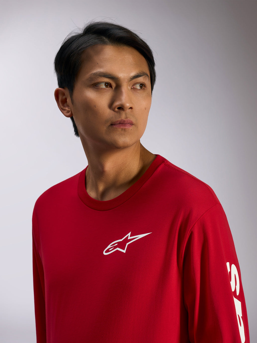 Alpinestars Trackside CSF Tee, camiseta de manga larga, roja con logo de Alpinestars blanco en el pecho y letras en la manga, estilo streetwear casual inspirado en el motor, retrato de estilo de vida