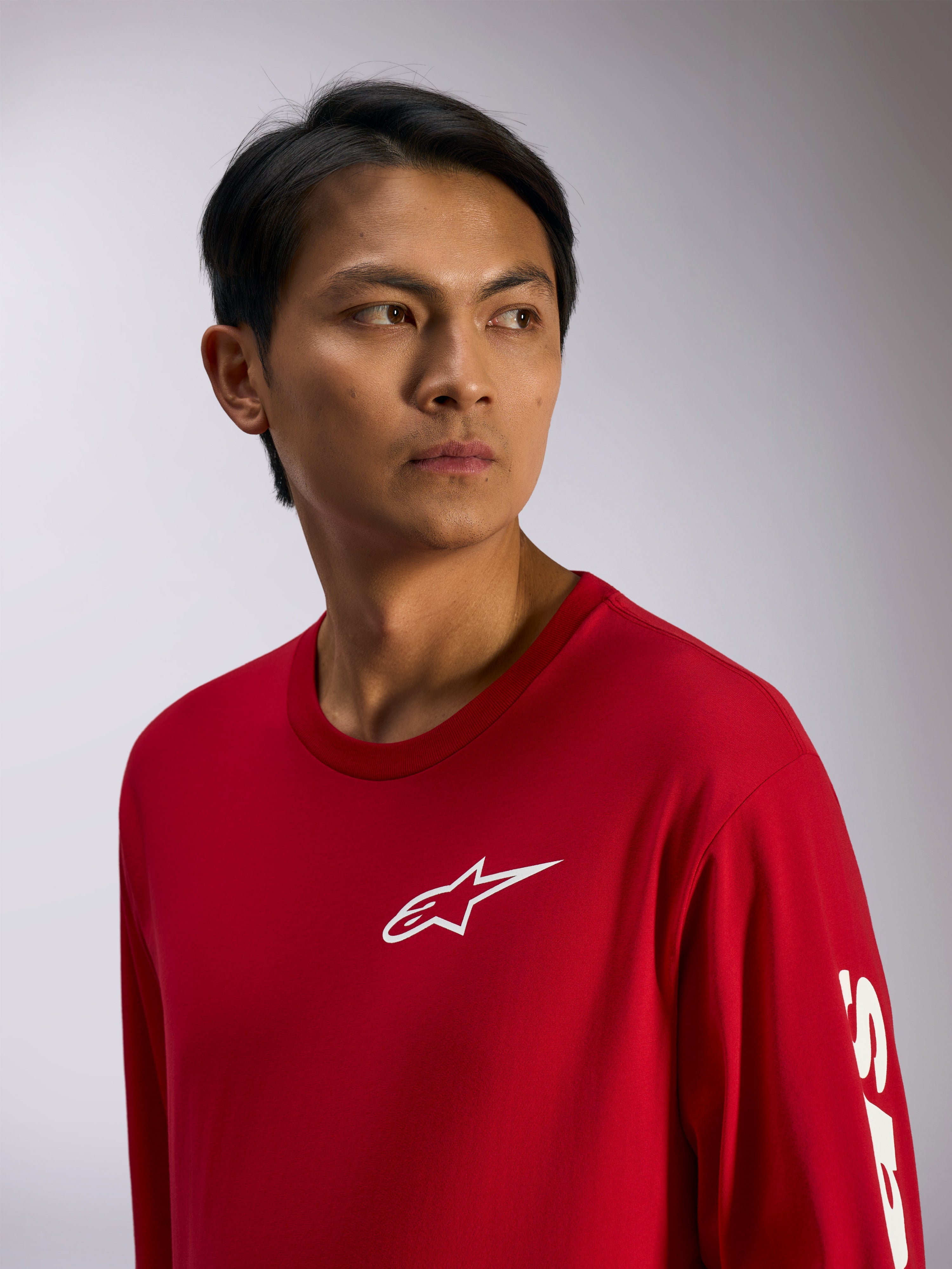 Alpinestars Trackside CSF Tee, camiseta de manga larga, roja con logo de Alpinestars blanco en el pecho y letras en la manga, estilo streetwear casual inspirado en el motor, retrato de estilo de vida