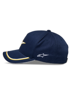 Alpinestars Gorra Snapback Ascension, azul marino y dorado, perfil lateral con visera curva y doble ribete sutache en dorado y blanco, logotipo lateral bordado, estilo casual motorsport