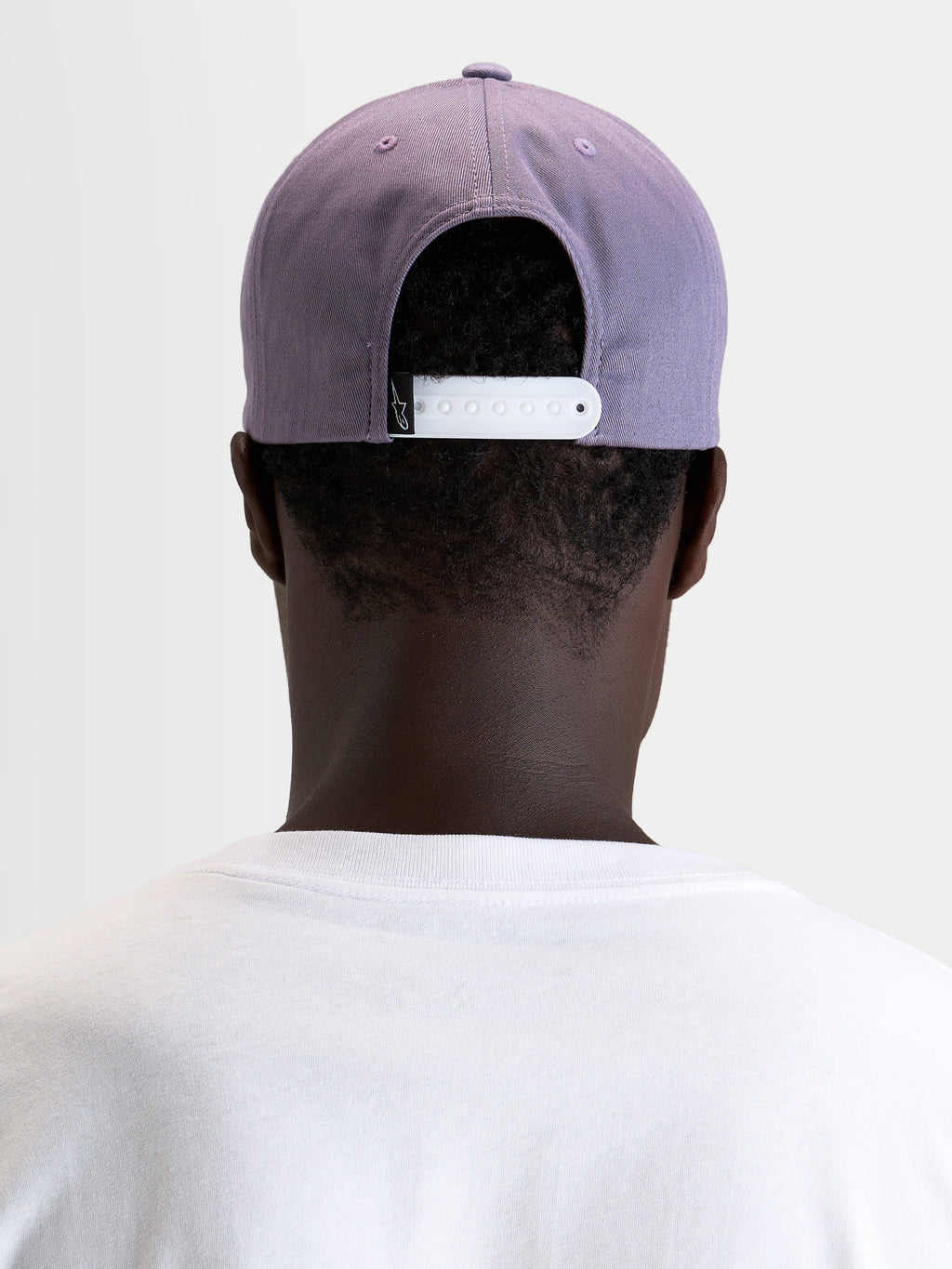 Gorra Ageless Snapback Alpinestars, gorra sportswear, morada con cierre ajustable blanco, vista trasera en modelo