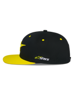 Gorra Snapback Alpinestars Thickness, negra y amarilla de alta visibilidad, perfil lateral, corona estructurada con ojales amarillos y visera plana amarilla, logo Astars bordado en el lateral, accesorio casual de motorsport
