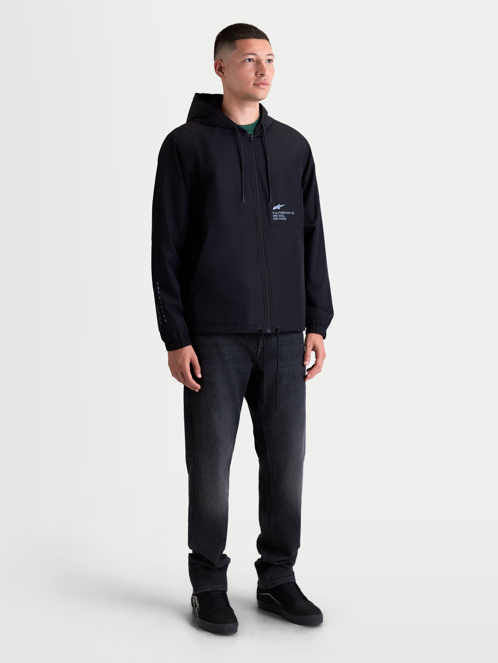 Alpinestars Speeder Resolve, chaqueta cortavientos ligera para hombre, negra, con interior de malla, capucha ajustable y logotipos de la marca en el pecho y la manga, prenda de sportswear mostrada en modelo para uso urbano.