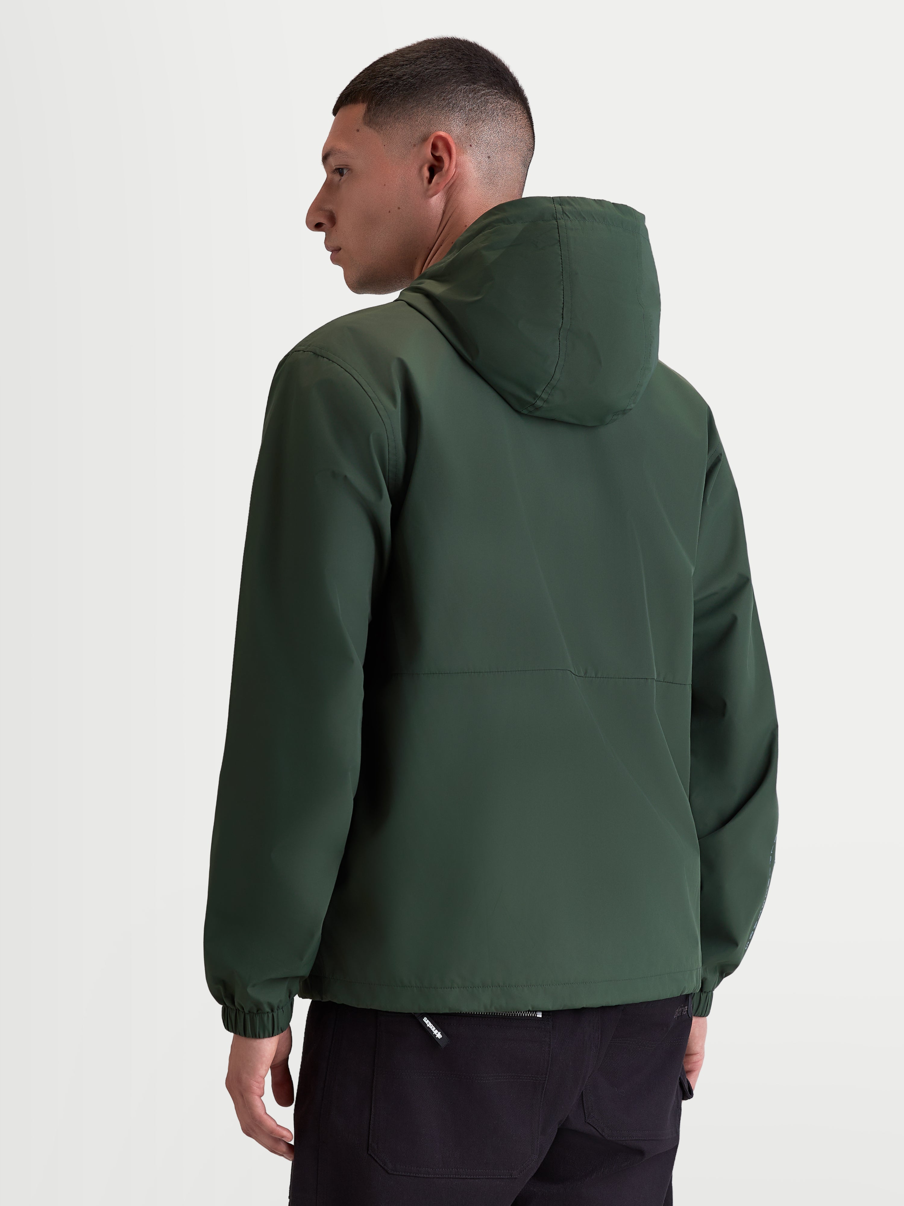 Alpinestars Chaqueta Cortavientos Speeder Resolve, cortavientos ligero para hombre de uso urbano, verde pino, poliéster con forro de malla, vista trasera en modelo mostrando el diseño limpio de la espalda, la capucha y los puños elásticos