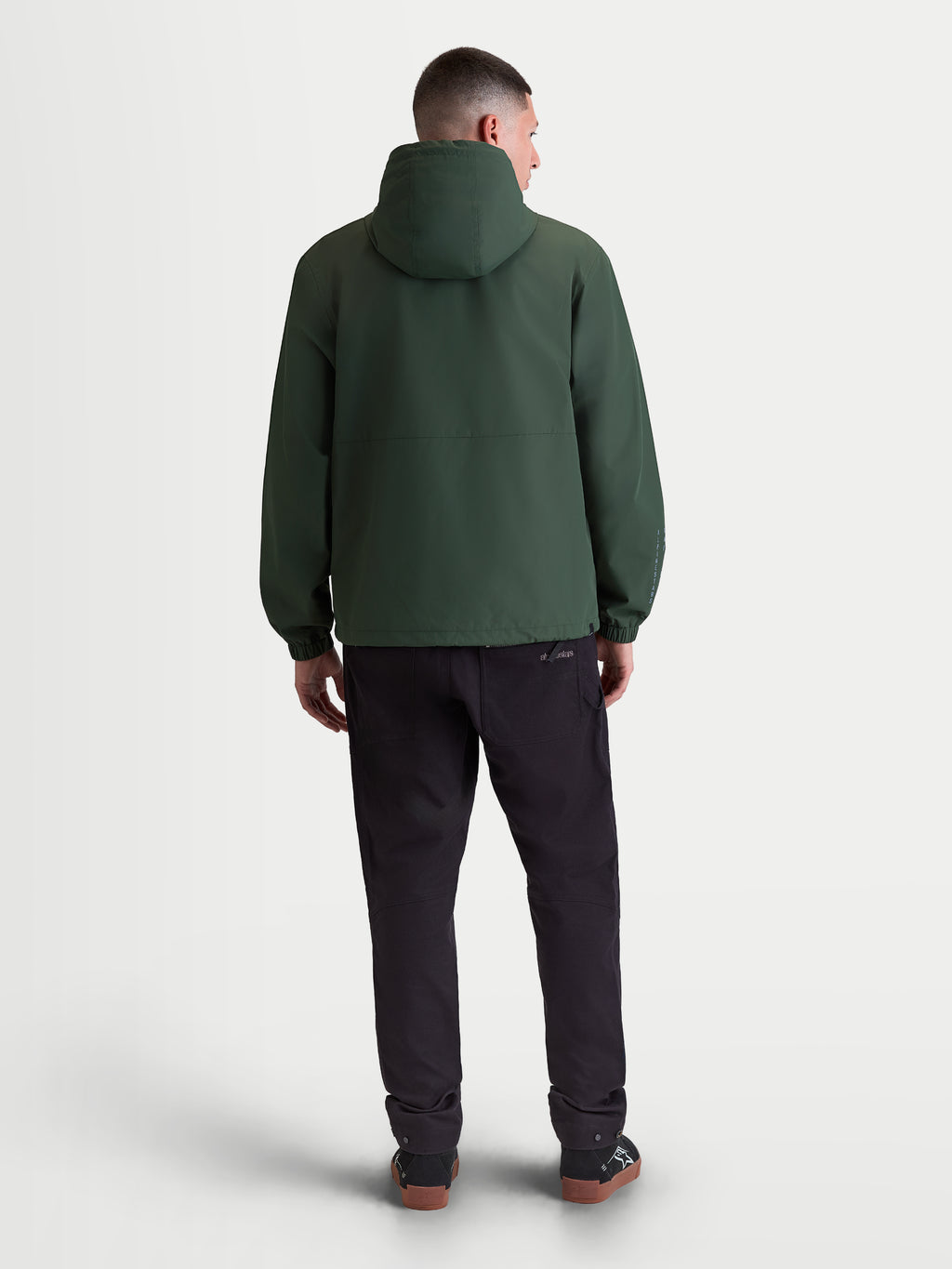Alpinestars chaqueta cortavientos Speeder Resolve, chaqueta ligera de sportswear para hombre en color verde pino, diseño de textil cortavientos, vista trasera que muestra la capucha y los puños elásticos.
