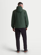 Alpinestars chaqueta cortavientos Speeder Resolve, chaqueta ligera de sportswear para hombre en color verde pino, diseño de textil cortavientos, vista trasera que muestra la capucha y los puños elásticos.