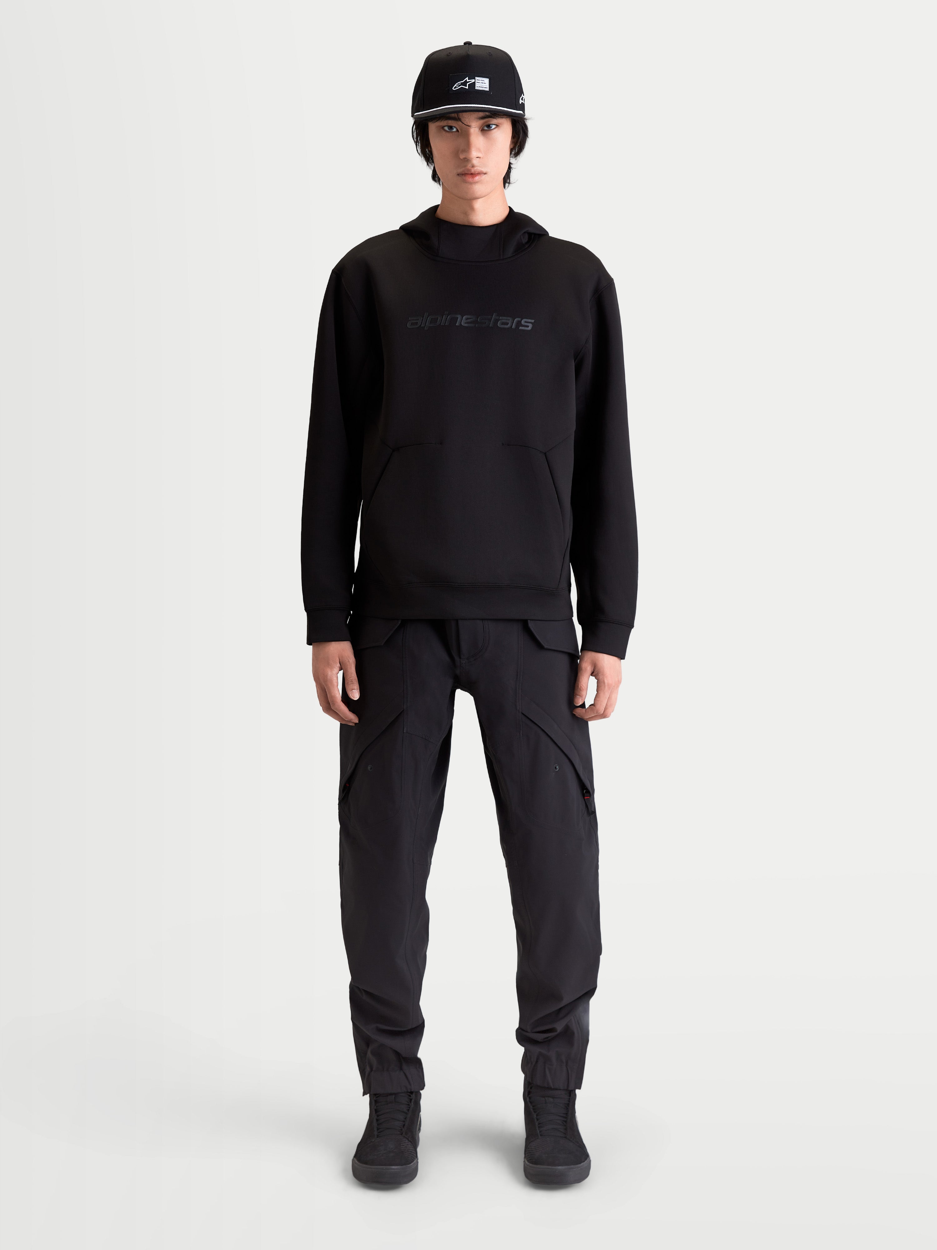 Alpinestars Sudadera con capucha Datrix, sudadera de estilo casual inspirado en el motorsport para hombre, color negro, con logotipo tonal en el pecho, forro polar de doble cara y bolsillo frontal con detalle de pliegue, mostrado en modelo