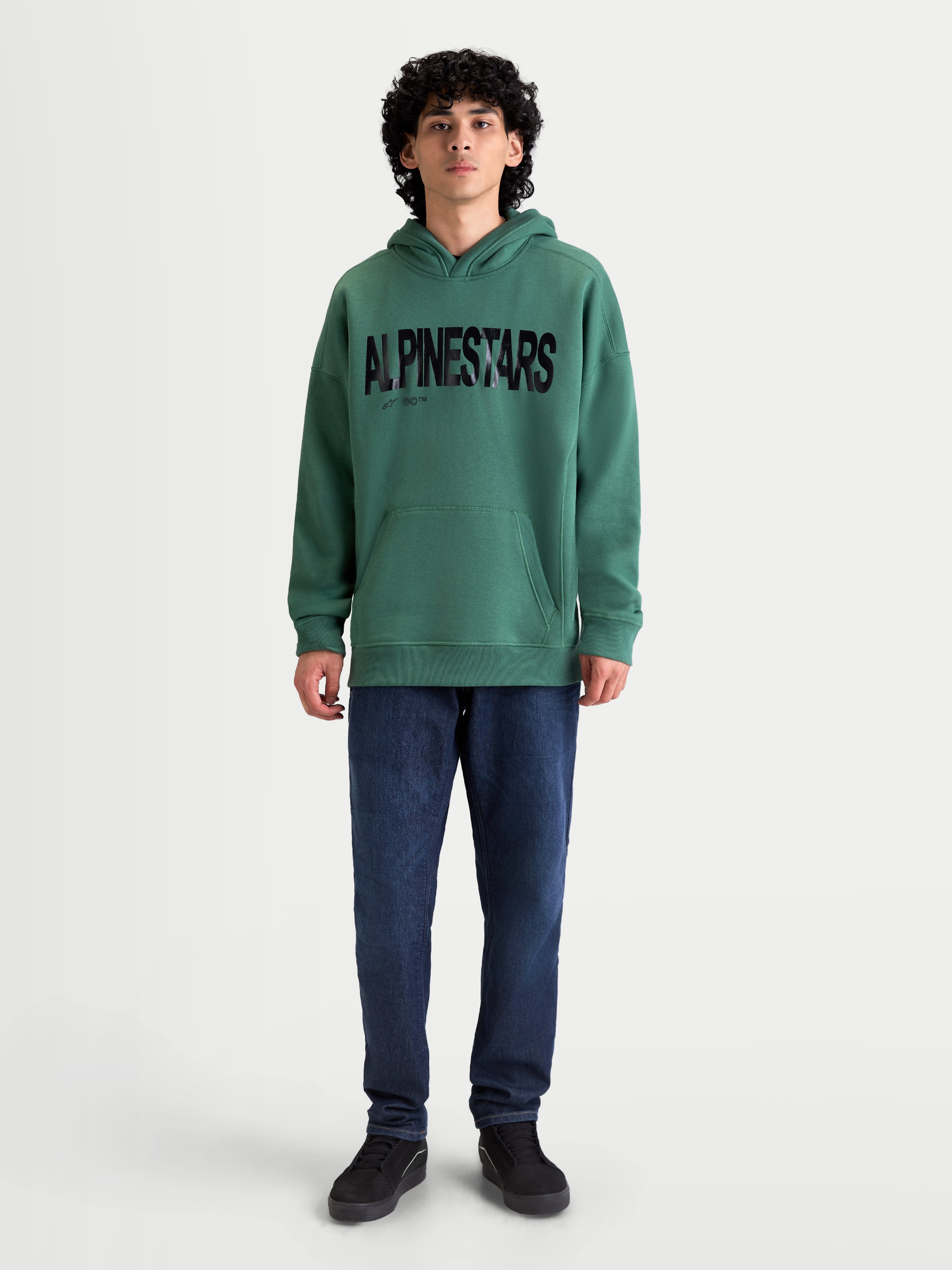 Alpinestars sudadera con capucha Shaw Oversized, ropa deportiva casual, para hombre, verde con logotipo texturizado negro, ajuste oversized, forro polar de algodón y poliéster reciclado, con bolsillo canguro y capucha forrada, mostrada con modelo.