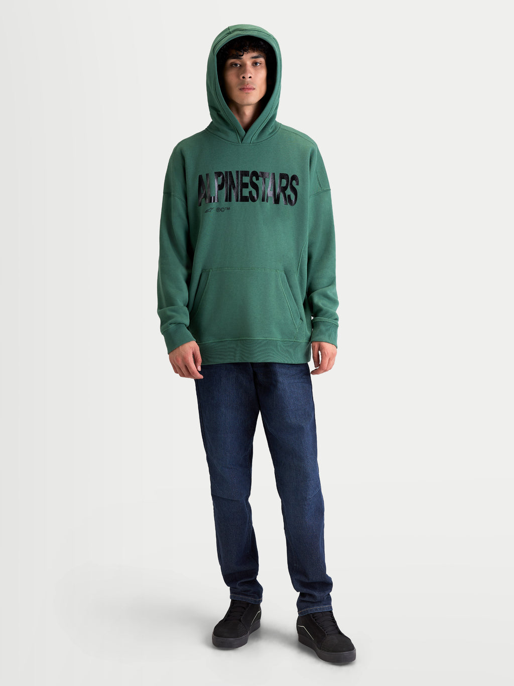 Alpinestars sudadera con capucha Shaw Oversized, ropa deportiva de ajuste relajado, verde con logotipo texturizado negro, vista frontal en modelo, forro polar de algodón y poliéster reciclado con bolsillo canguro.