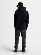 Alpinestars Sudadera Con Capucha Velocifier, ropa deportiva para hombre de forro polar, negra con logotipos blancos en los hombros, vista trasera en modelo que muestra la capucha, confeccionada en mezcla de algodón y poliéster reciclado.