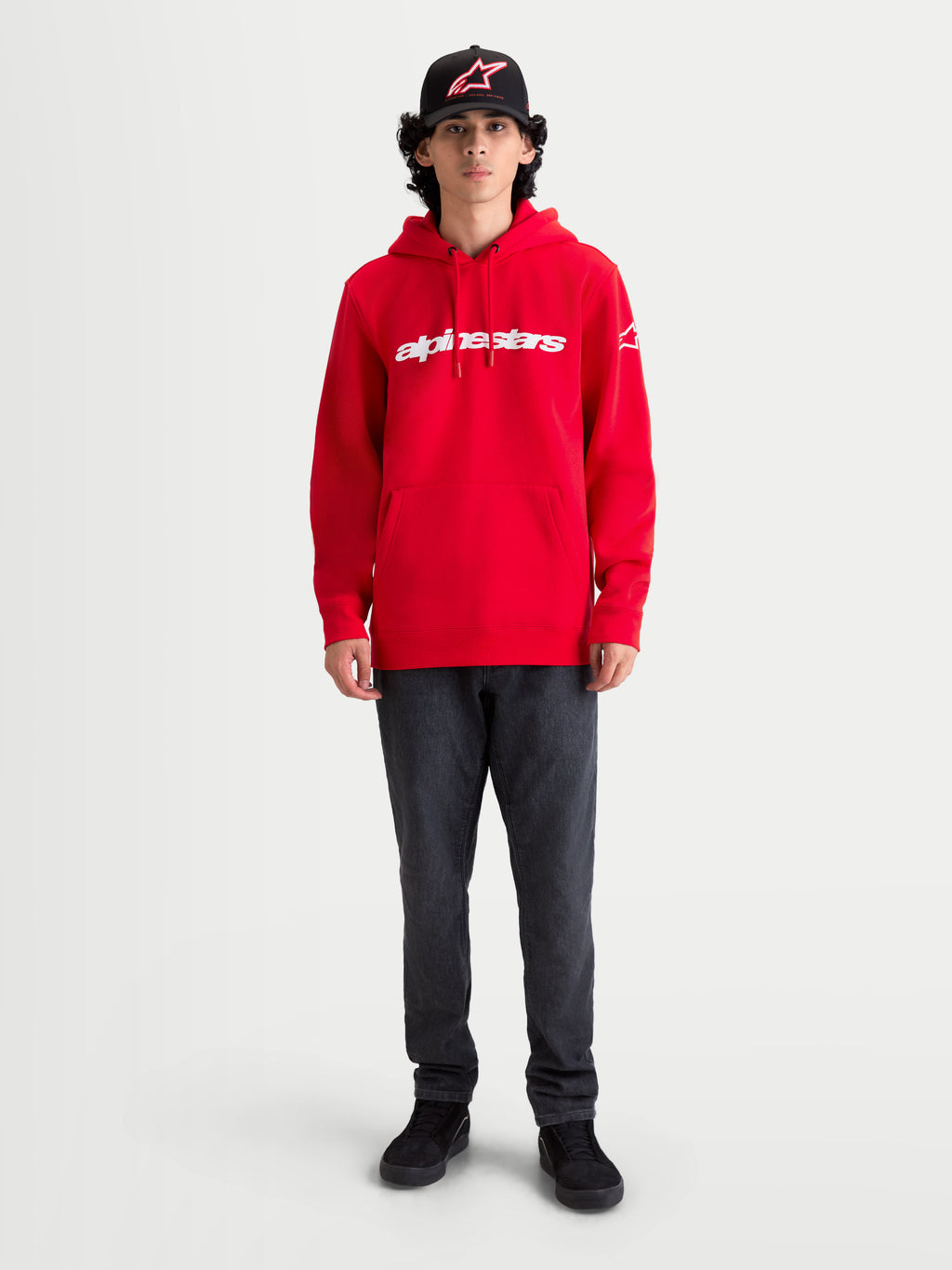 Alpinestars Sudadera con capucha Race Wordmark, sudadera de forro polar roja y blanca con logotipo wordmark en el pecho, capucha con cordón ajustable y bolsillo de canguro, llevada por un modelo para un estilo casual de inspiración motorsport.