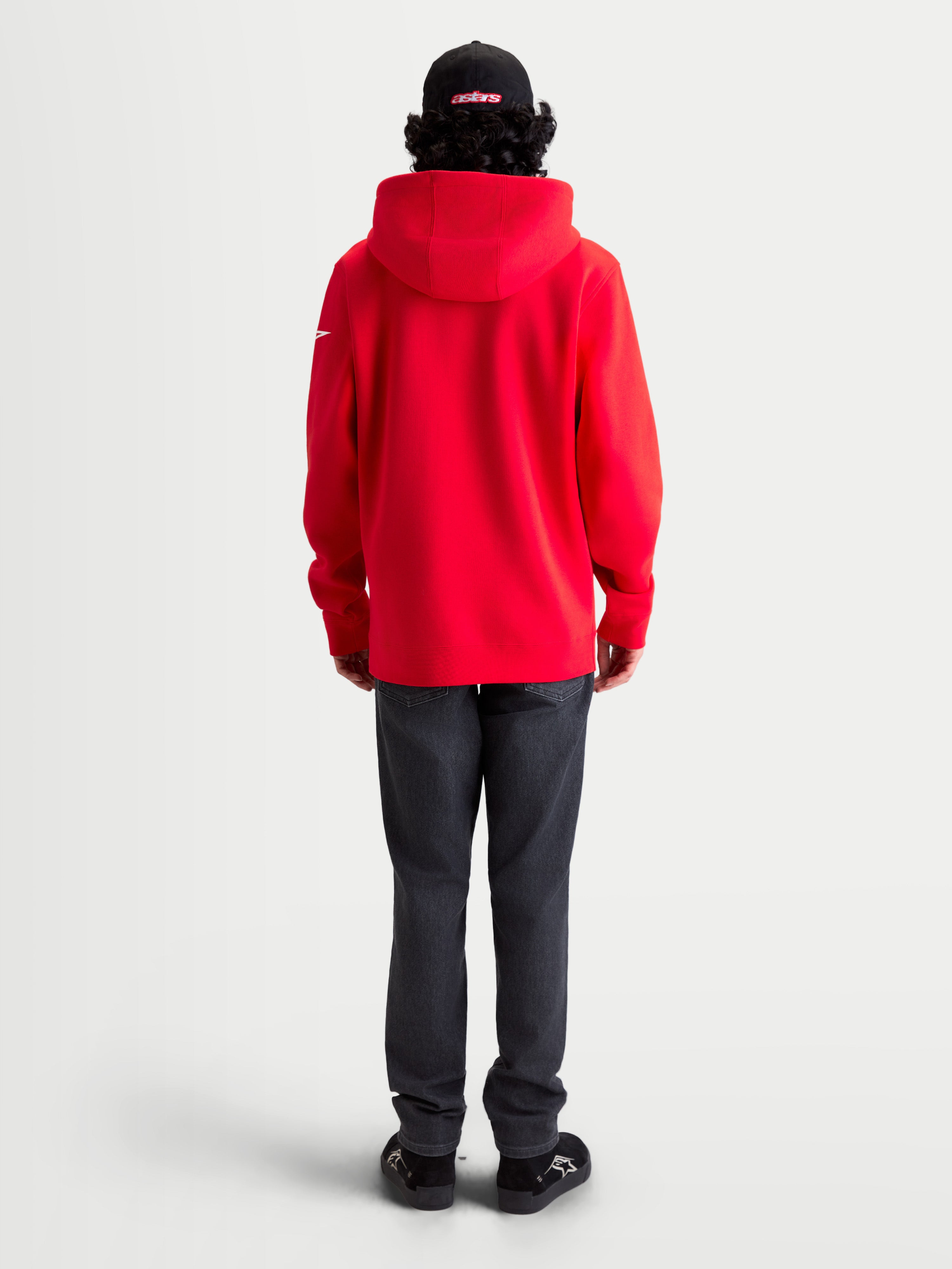 Alpinestars Sudadera con capucha Race Wordmark, sudadera de forro polar tipo pulóver, roja con detalles blancos, vista trasera en modelo con capucha forrada y logotipo Ageless en la manga, ropa casual inspirada en el motorsport