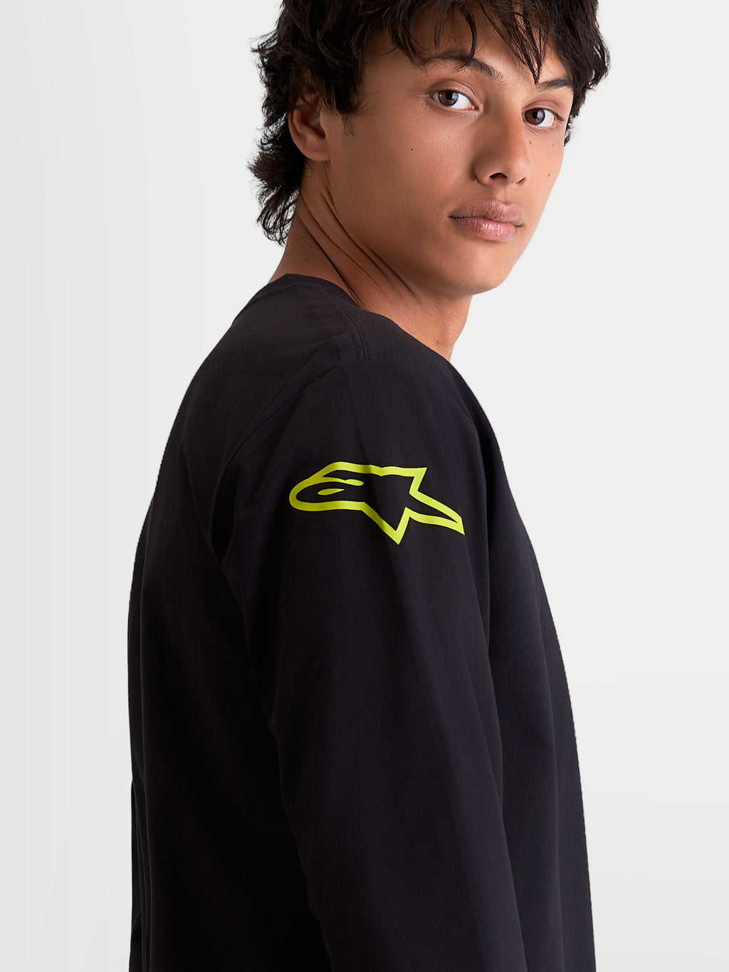 Alpinestars Velocifier CSF, camiseta de mangas largas para hombre, negra con un logotipo Astars amarillo vibrante en el hombro, ropa deportiva casual de estilo motorsport, vista de cerca en modelo