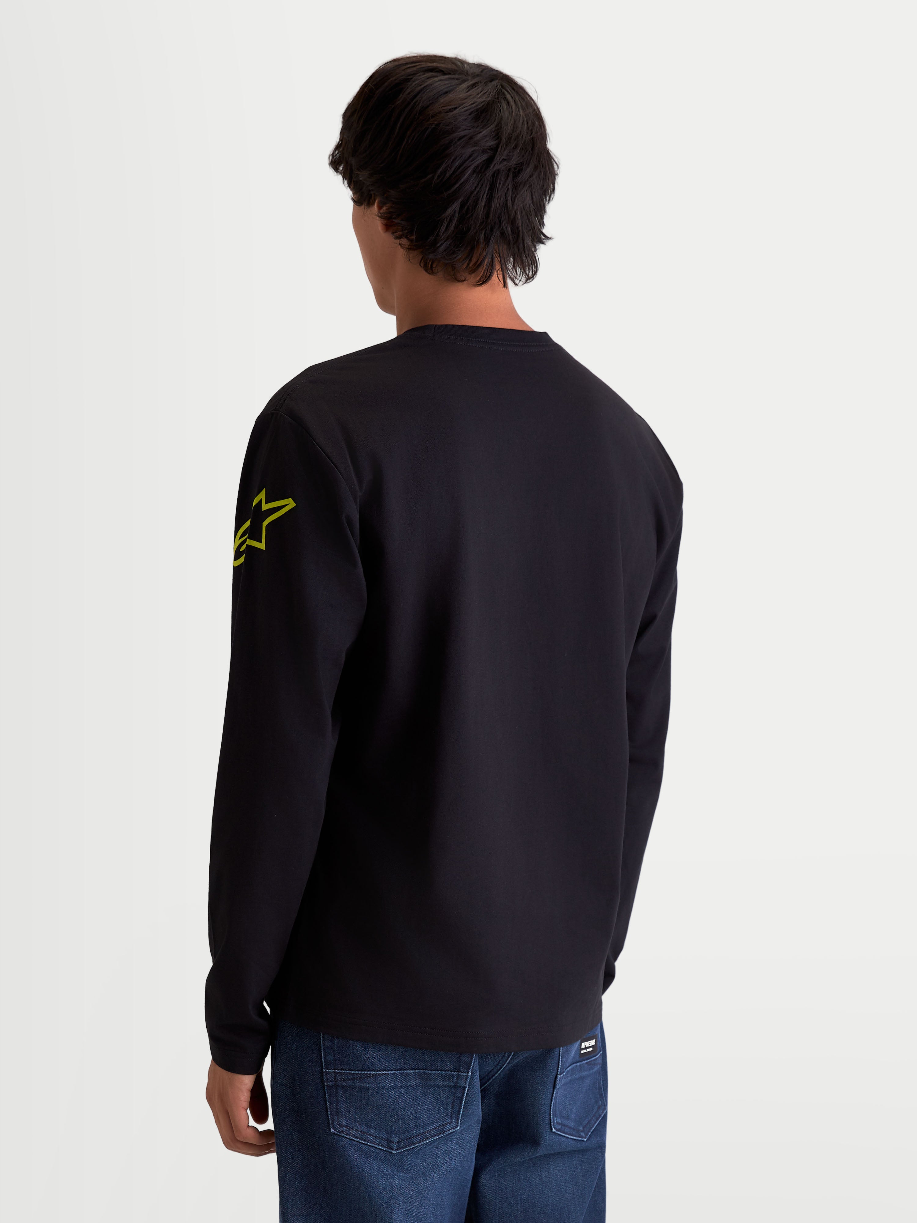 Alpinestars Velocifier CSF, camiseta de mangas largas sportswear, ropa casual unisex, negra y amarilla, mezcla de algodón y poliéster reciclado, vista trasera en modelo que muestra el logotipo Astars en el brazo y puños de canalé