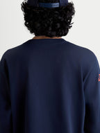 Alpinestars camiseta Velocifier CSF, camiseta de mangas largas en azul marino, vista trasera en modelo con cuello redondo de canalé, ropa deportiva casual inspirada en el motorsport fabricada en mezcla de algodón y poliéster reciclado.