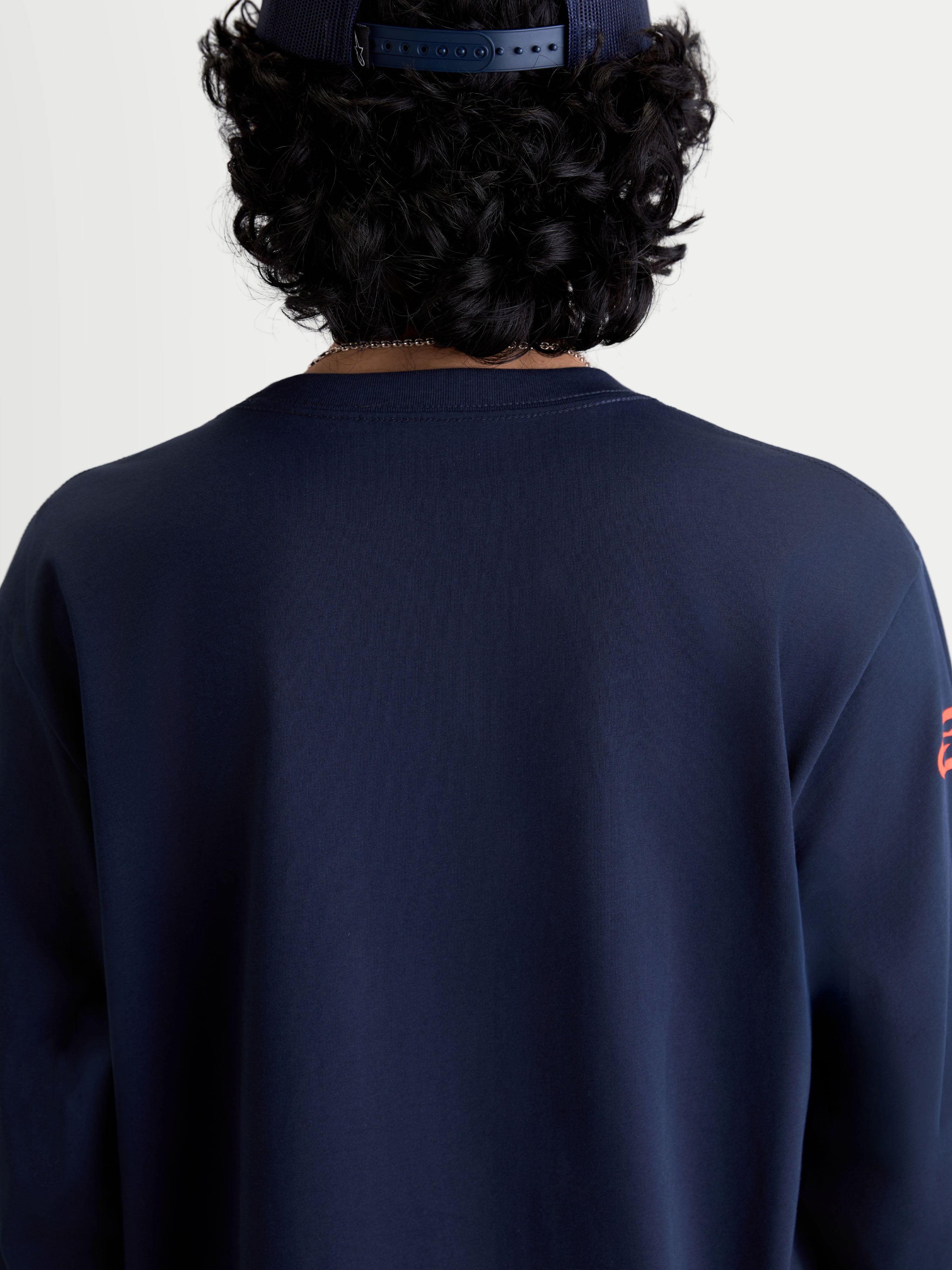 Alpinestars camiseta Velocifier CSF, camiseta de mangas largas en azul marino, vista trasera en modelo con cuello redondo de canalé, ropa deportiva casual inspirada en el motorsport fabricada en mezcla de algodón y poliéster reciclado.