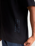 Alpinestars Chalk Oversized CSF Tee, Casual Motorsport Sportswear T-Shirt, Black with vertical Blue side branding text 'ALPINESTARS ONE GOAL ONE VISION', close-up detail shot on model.