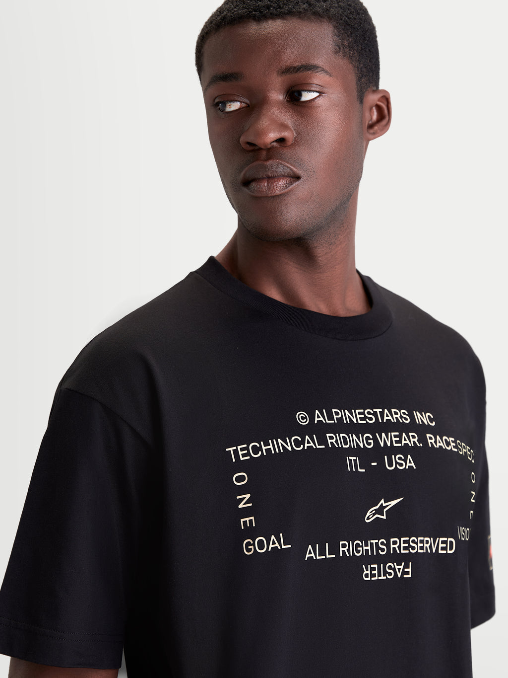 Alpinestars Infinity Oversized CSF Tee, Men's Short Sleeve Sportswear T-shirt, Black, featuring a soft-hand front chest graphic with Alpinestars branding and motorsport-inspired text, close-up on model for a premium off-bike look.