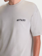 Alpinestars Latitude Oversized CSF, camiseta de mangas cortas para hombre, color gris cemento con logotipo ASTARS negro en el pecho, estilo casual con ajuste oversized, confeccionada en mezcla de algodón y poliéster, vista en modelo.