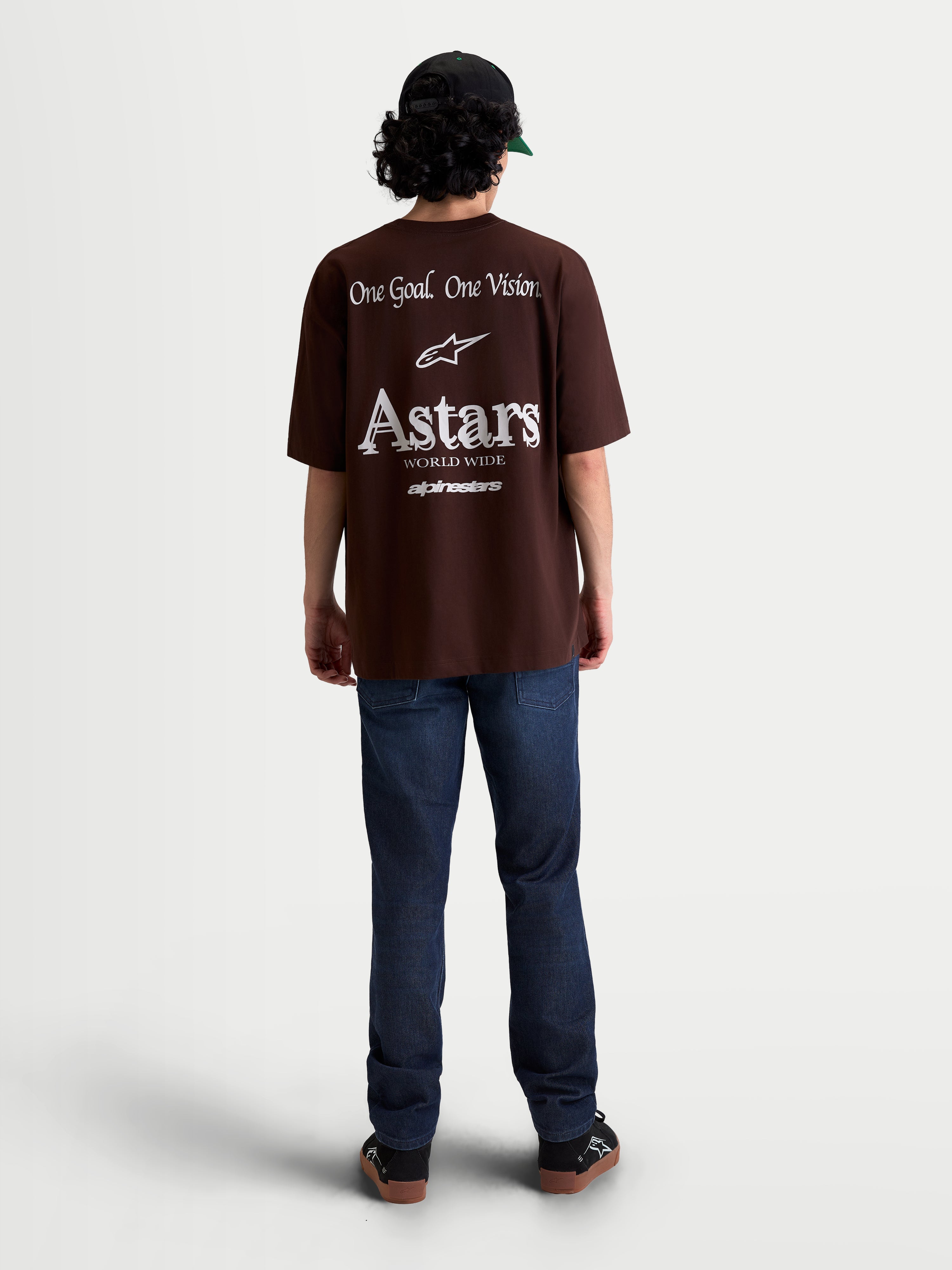 Alpinestars Camiseta Oversized Post CSF, camiseta de mangas cortas, marrón, con gráficos blancos en la espalda 'One Goal. One Vision.' y branding Astars World Wide, ajuste oversized para estilo casual de ropa deportiva.