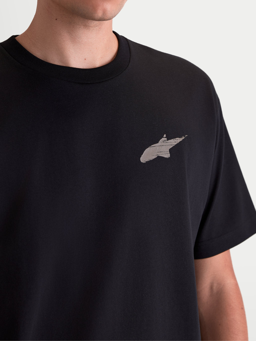 Alpinestars Checkback Oversized CSF, camiseta de manga corta de estilo sportswear y ajuste oversized, negra, mezcla de algodón y poliéster, detalle en primer plano del pecho con el logotipo Astars y acabado de impresión suave, estilo motorsport casual