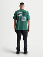 Alpinestars Checkback Oversized CSF, camiseta de mangas cortas de estilo sportswear, verde con un llamativo gráfico de cuadros en la espalda, ajuste relajado, vista posterior en modelo