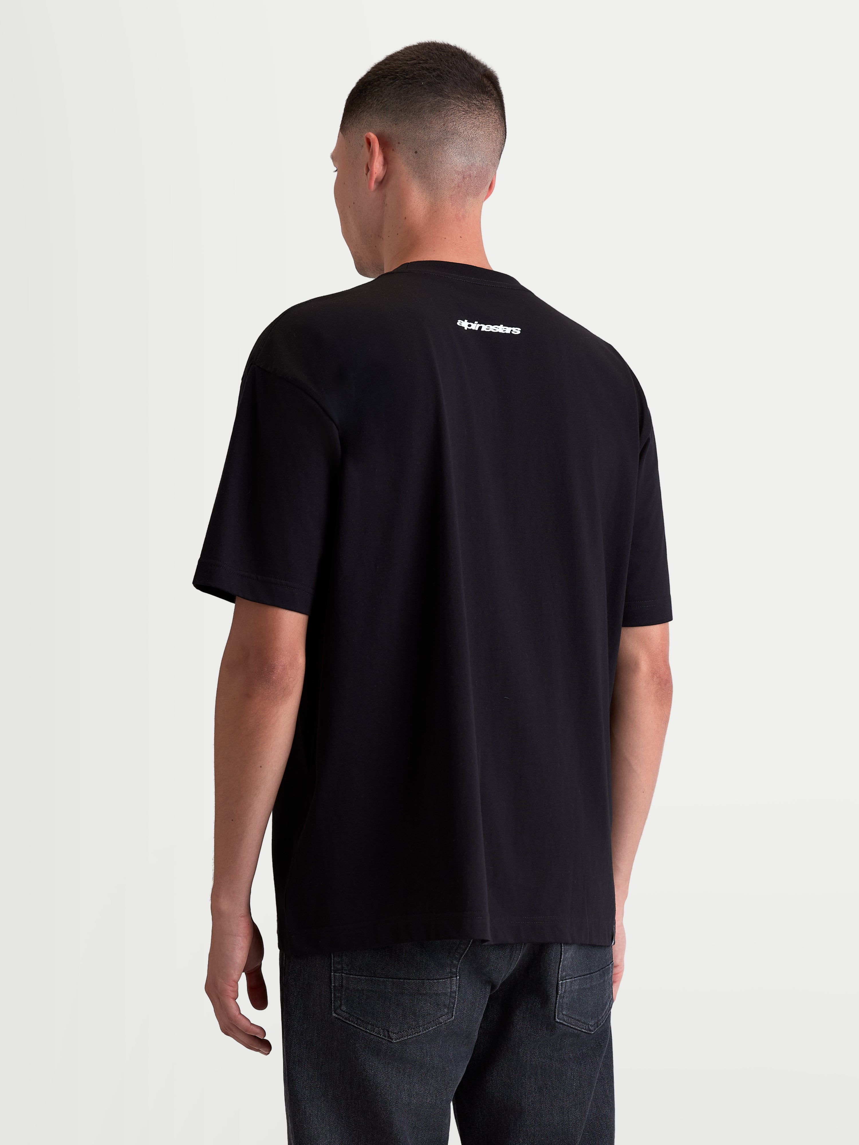 Alpinestars Prelude Oversized CSF, camiseta de mangas cortas para hombre, negra con logotipo Alpinestars blanco en la espalda, corte holgado, construcción de mezcla de algodón y poliéster, vista trasera en modelo, ropa deportiva.
