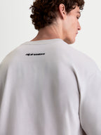 Alpinestars Prelude Oversized CSF, camiseta de mangas cortas, gris cemento y negra, vista de la espalda en modelo mostrando el logotipo de Alpinestars, corte holgado oversized, mezcla de algodón y poliéster