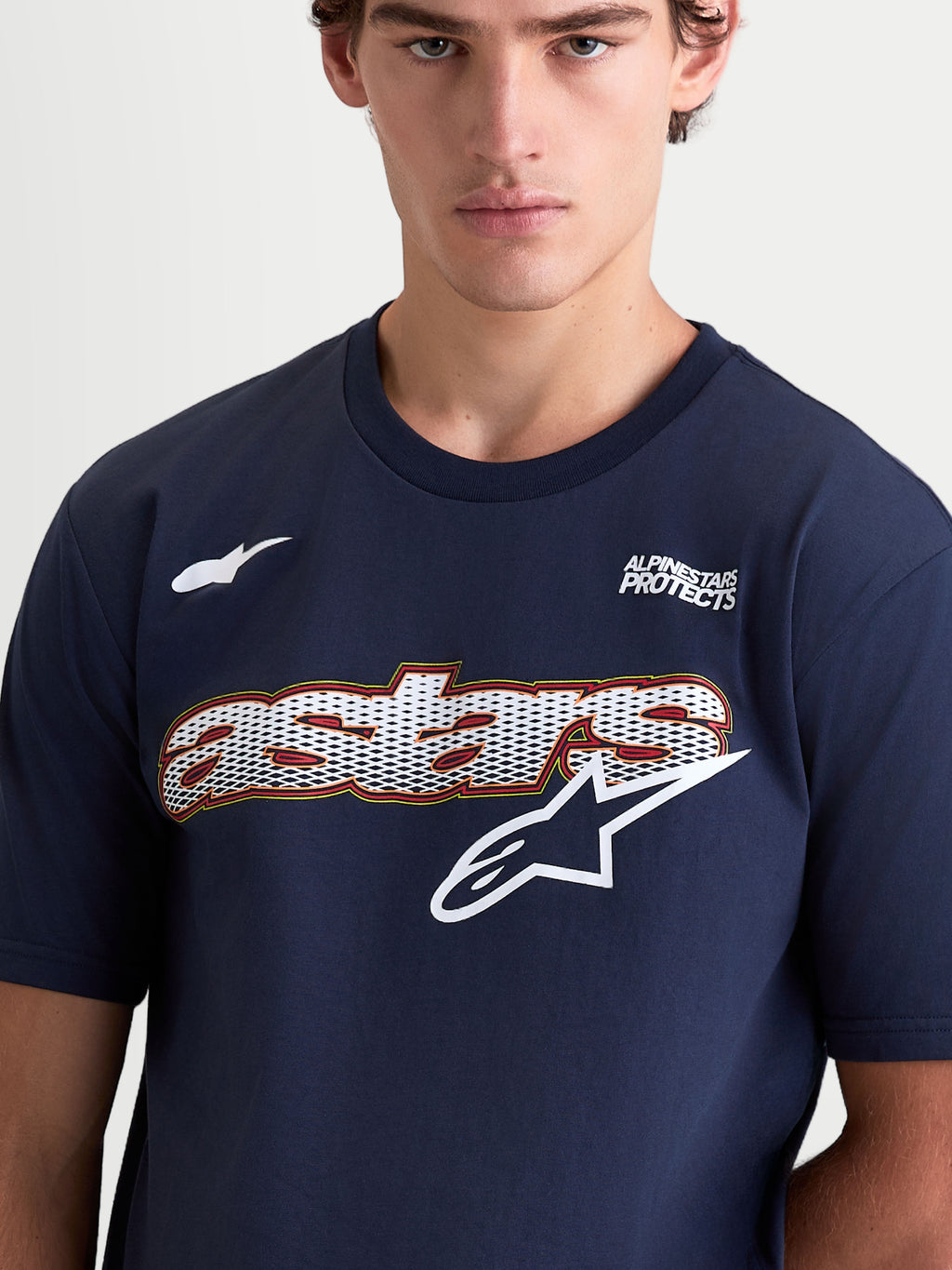 Alpinestars Cypress CSF, camiseta de mangas cortas para hombre, azul marino y blanca, con gráfico de logotipo Astars con relleno de malla y texto Alpinestars Protects en el pecho, primer plano en modelo.